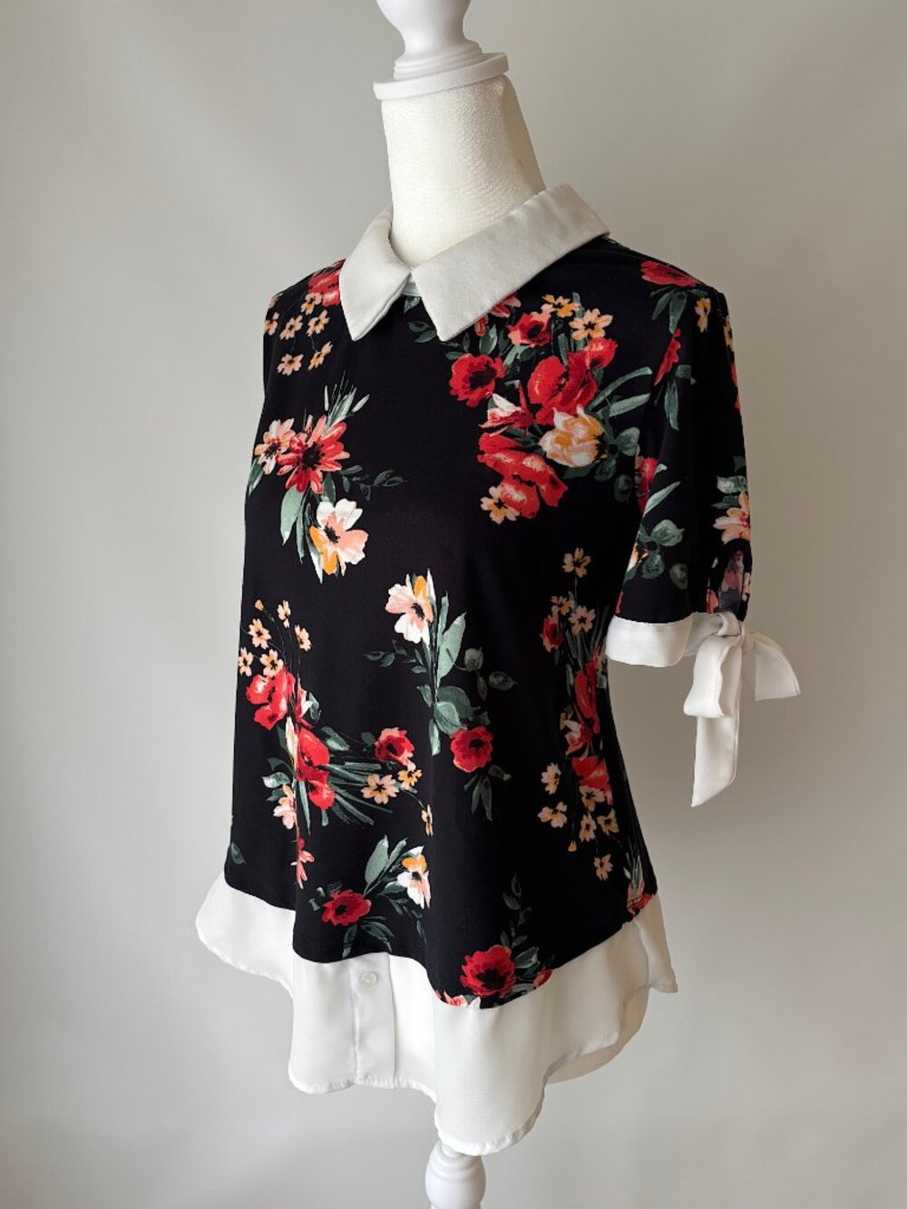 black floral short-sleeve top with white collar and bow cuffs